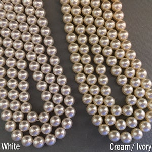 May include: Two strands of pearl beads, one white and one cream/ivory. The beads are round and smooth.
