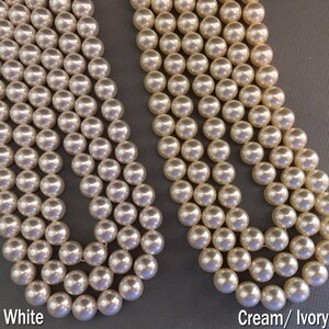 May include: Two strands of faux pearl beads, one white and one cream/ivory. The beads are round and smooth.