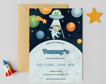 Könnte beinhalten: Eine Einladungskarte mit Weltraum-Thema, die einen Astronauten, Planeten und ein UFO zeigt. Die Einladung lautet "Tommy's first trip around the sun" mit Veranstaltungsdetails. Eine Rakete und ein Stern liegen neben der Einladung. Ein brauner Umschlag befindet sich dahinter.