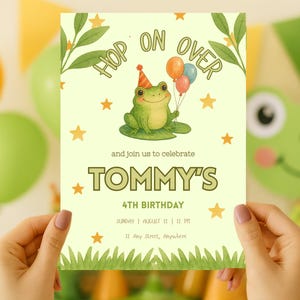 May include: A birthday party invitation featuring a green frog wearing a party hat and holding balloons. The invitation reads "Hop on Over" and includes the text "Tommy's 4th Birthday" with date, time, and location details. The invitation is held by a person.