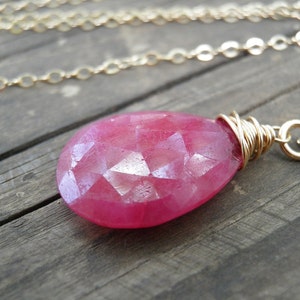 May include: A pink gemstone pendant necklace with a gold chain. The gemstone is faceted and has a teardrop shape.