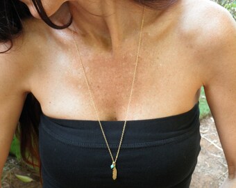 May include: A gold chain necklace with a small turquoise stone and a feather pendant.