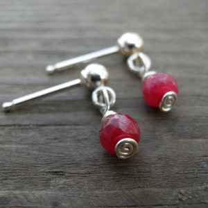 May include: A pair of silver earrings with red gemstone drops. The earrings are made with wire wrapped around the gemstones.