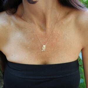 May include: A gold chain necklace with a small owl pendant. The owl is facing forward with its wings spread out.
