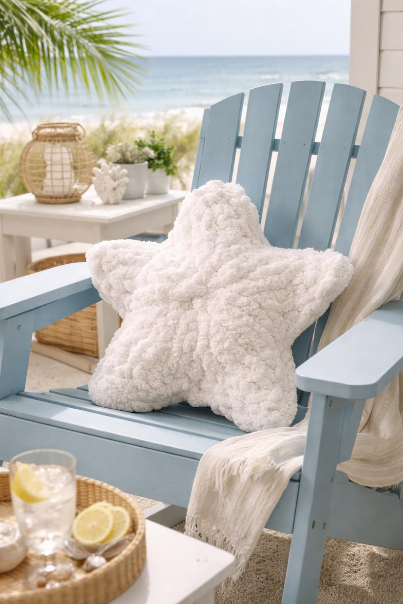 Puede incluir: Un gran coj&iacute;n blanco con forma de estrella de mar descansa sobre una silla Adirondack azul claro. La silla est&aacute; en una terraza con vista a una playa y al oc&eacute;ano. Una manta blanca est&aacute; sobre la silla. Una bandeja con un vaso de agua y rodajas de lim&oacute;n est&aacute; cerca.