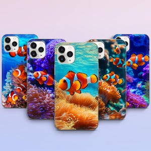 May include: A collection of phone cases featuring vibrant underwater scenes. Each case showcases a different design with clownfish swimming among coral reefs. The cases have a glossy finish and are in various shades of blue, orange, and purple.