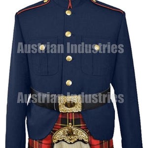 Op de afbeelding: Marineblau militair jack met gouden knopen en rode bies. De jas heeft twee voorzakken en wordt gecombineerd met een zwarte riem en een rood-zwarte geruite kilt. De tekst "Austrian Industries" is zichtbaar.