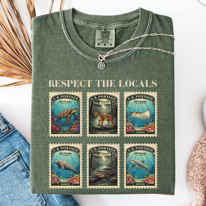 May include: Green Comfort Colors t-shirt with the text "RESPECT THE LOCALS" and six postage stamp designs featuring sea creatures. The stamps read "U.S. Postage 10 Cents" and depict a sea turtle, panther, stingray, manatee, alligator, and dolphin.