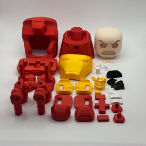 Puede incluir: Un conjunto de componentes de armadura de Iron Man impresos en 3D, en rojo y amarillo. El conjunto incluye un casco, torso, piezas de piernas y una cabeza de expresi&oacute;n neutra. Tambi&eacute;n se incluyen varias piezas m&aacute;s peque&ntilde;as.