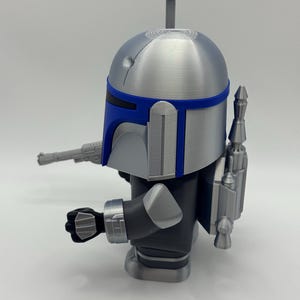 Peut inclure: Figurine argent&eacute;e et bleue d'un personnage avec un casque, un jetpack et un blaster. La figurine a un casque bleu et argent&eacute; avec une antenne grise. La figurine porte une combinaison noire et argent&eacute;e.