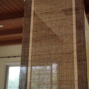 Puede incluir: Un camino de mesa rectangular con textura tejida, que presenta un panel central de rayas verticales de color beige claro flanqueado por dos bordes anchos de color marr&oacute;n oscuro a cada lado. La tela tiene un patr&oacute;n de tejido grueso visible.