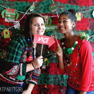 May include: Two people wearing festive Christmas jumpers with lights and decorations. One person is holding a sign that says "Nice".