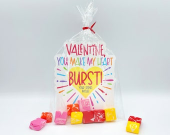 May include: A clear plastic bag filled with colorful candies and a Valentine's Day card that reads "Valentine, you make my heart burst!" with a yellow heart and rainbow accents.