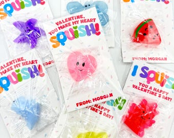 Pode incluir: Uma coleção de brinquedos squishy do Dia dos Namorados em sacos plásticos transparentes. Os brinquedos têm várias formas e cores, incluindo um coração, uma fatia de melancia e uma estrela do mar. Cada saco tem um cartão que diz "Valentine, You Make My Heart Squish!"