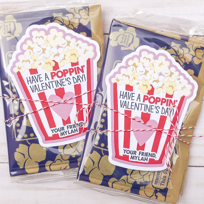 May include: Two Valentine's Day gift bags with popcorn-themed gift tags. The tags are red and white with a pink heart and the text "Have a Poppin' Valentine's Day!" and "Your Friend, Mylah".