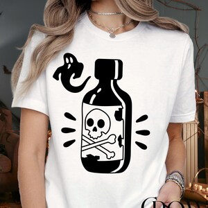 May include: White t-shirt featuring a black graphic of a poison bottle with a skull and crossbones, and a ghost. The shirt has short sleeves and a crew neck. The text "CROWN CUSTOM SHIRT" is at the bottom.