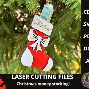 Op de afbeelding: Een rood-witte kerstsok-ornament met een witte strik en de naam "Michae" bovenaan. De sok hangt aan een kerstboomtak en bevat een rekening. De tekst "LASER CUTTING FILES" en "Christmas money stocking!" staat onderaan.