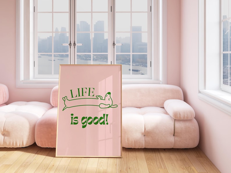 Peut inclure: Affiche rose encadr&eacute;e avec l'inscription verte &laquo; LIFE is good! &raquo; et une illustration de teckel. L'affiche est pr&eacute;sent&eacute;e dans une pi&egrave;ce avec un canap&eacute; rose et un sol en bois.