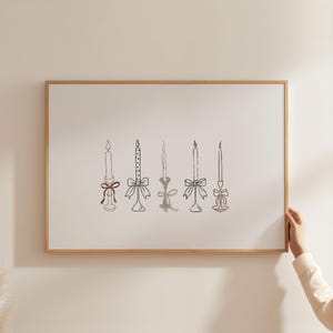 May include: A framed print with six black and white candle illustrations. Each candle has a unique design, including bows and different candlestick holders. The artwork is set against a light beige background and framed in natural wood.