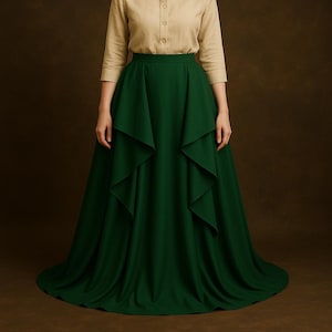 May include: A long, flowing emerald green skirt with a layered design. The skirt is paired with a tan button-down shirt with three-quarter sleeves. The skirt's fabric drapes elegantly, creating a full silhouette. The outfit is suitable for formal occasions.