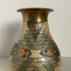 May include: A brass vase with a geometric pattern in shades of green, gold, and black. The vase has a round body and a narrow neck.