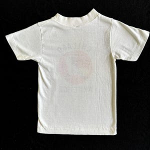 K&ouml;nnte beinhalten: Wei&szlig;es T-Shirt mit kurzen &Auml;rmeln und einem verblassten Aufdruck auf der Vorderseite.
