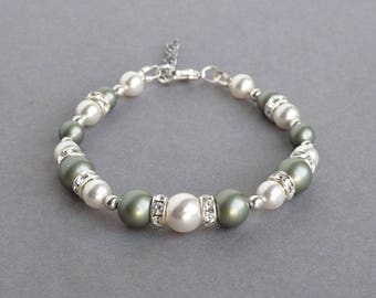 May include: A bracelet with alternating white and green pearls, accented with clear rhinestones. The bracelet has a silver clasp.