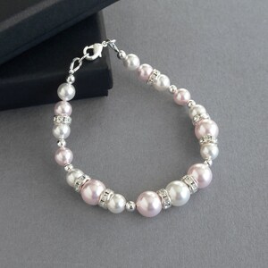 May include: A delicate bracelet featuring alternating pink and white pearls with rhinestone accents. The bracelet is made with a silver clasp.