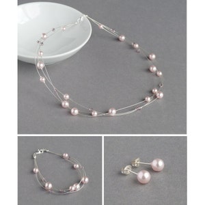 May include: A delicate jewellery set featuring a necklace, bracelet and earrings. The set is made with silver wire and features pink pearls and small purple crystals.