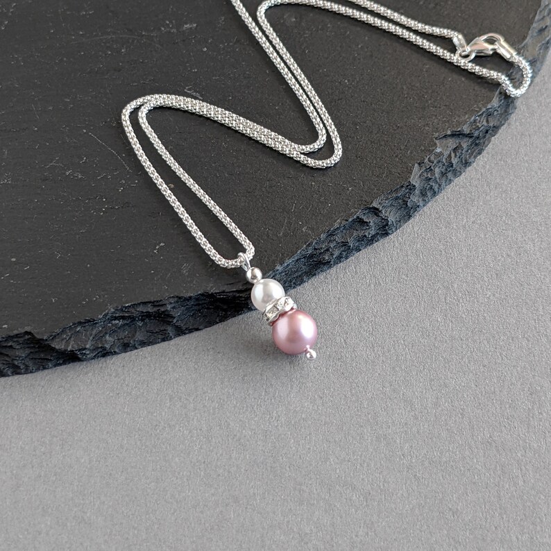 May include: A silver chain necklace with a pink and white pearl pendant. The pendant features a small crystal accent.