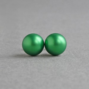 May include: A pair of green round stud earrings. The earrings are made of a smooth, shiny material.