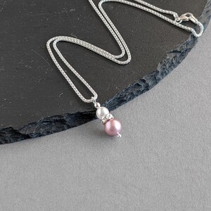 May include: A silver chain necklace with a pink and white pearl pendant.