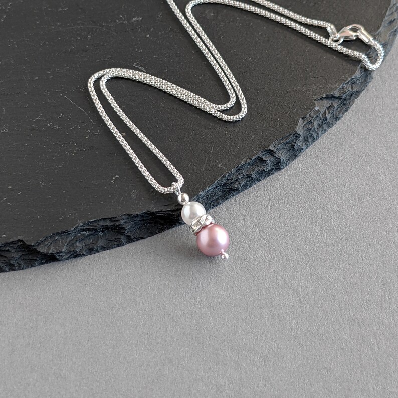 May include: A silver chain necklace with a pink and white pearl pendant.
