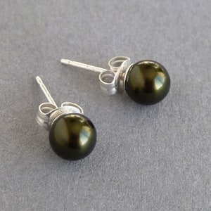 May include: A pair of silver stud earrings with dark green pearl accents.