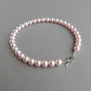 May include: A delicate pink pearl necklace with a silver toggle clasp.