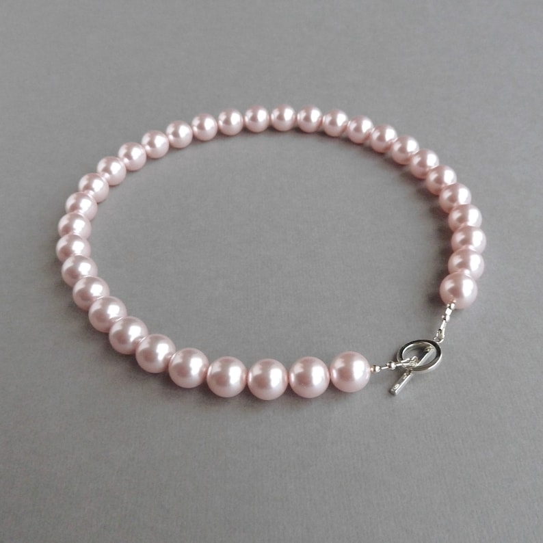 May include: A delicate pink pearl necklace with a silver toggle clasp.