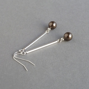 May include: A pair of silver dangle earrings with brown pearl accents.