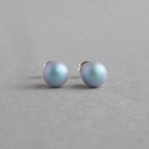 May include: A pair of iridescent blue stud earrings. The earrings are round and have a smooth, polished finish.
