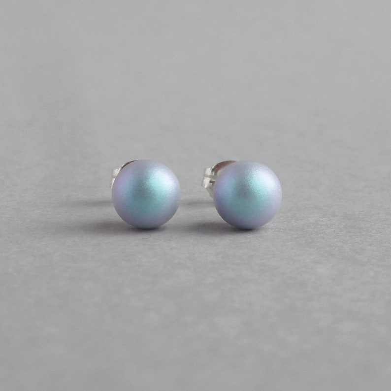 May include: A pair of iridescent blue stud earrings. The earrings are round and have a smooth, polished finish.