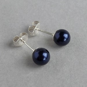 May include: A pair of silver stud earrings with dark blue pearl accents.