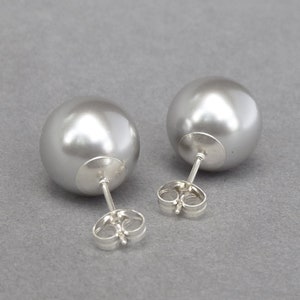 May include: A pair of silver stud earrings with large, round, pearl-like gray stones.