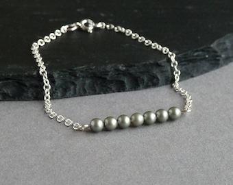 May include: A silver chain bracelet with a row of six gray pearls.