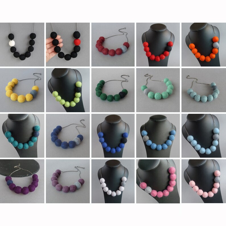May include: A collection of 20 felt ball necklaces in various colors, including black, white, red, orange, yellow, green, blue, purple, and gray. Each necklace features a single larger felt ball in a contrasting color.