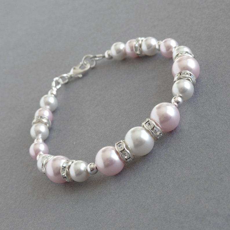 May include: A delicate bracelet made with alternating pink and white pearls, each accented with small clear rhinestones. The bracelet has a silver clasp.
