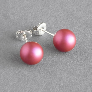 May include: A pair of silver stud earrings with a pink pearl on each earring.
