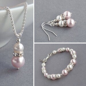May include: A set of pink and white pearl jewelry with a necklace, earrings, and bracelet. The jewelry features silver chain and accents.