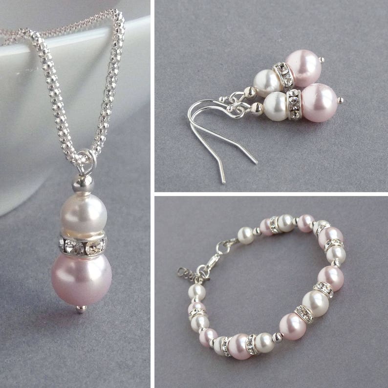 May include: A set of pink and white pearl jewelry with a necklace, earrings, and bracelet. The jewelry features silver chain and accents.