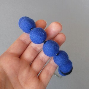 May include: A necklace made of blue felt balls strung together with black beads.