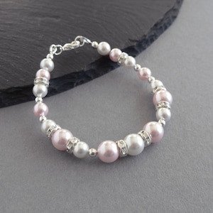 May include: A delicate bracelet featuring alternating pink and white pearls with clear rhinestone accents.