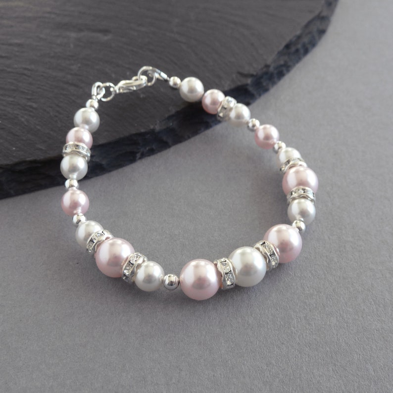 May include: A delicate bracelet featuring alternating pink and white pearls with clear rhinestone accents.
